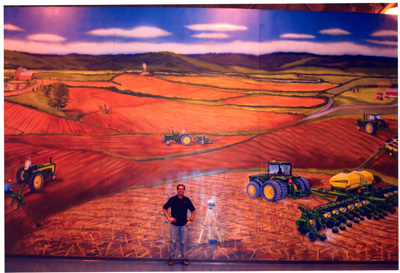 Mural of a man standing in the middle of a field during harvest time
